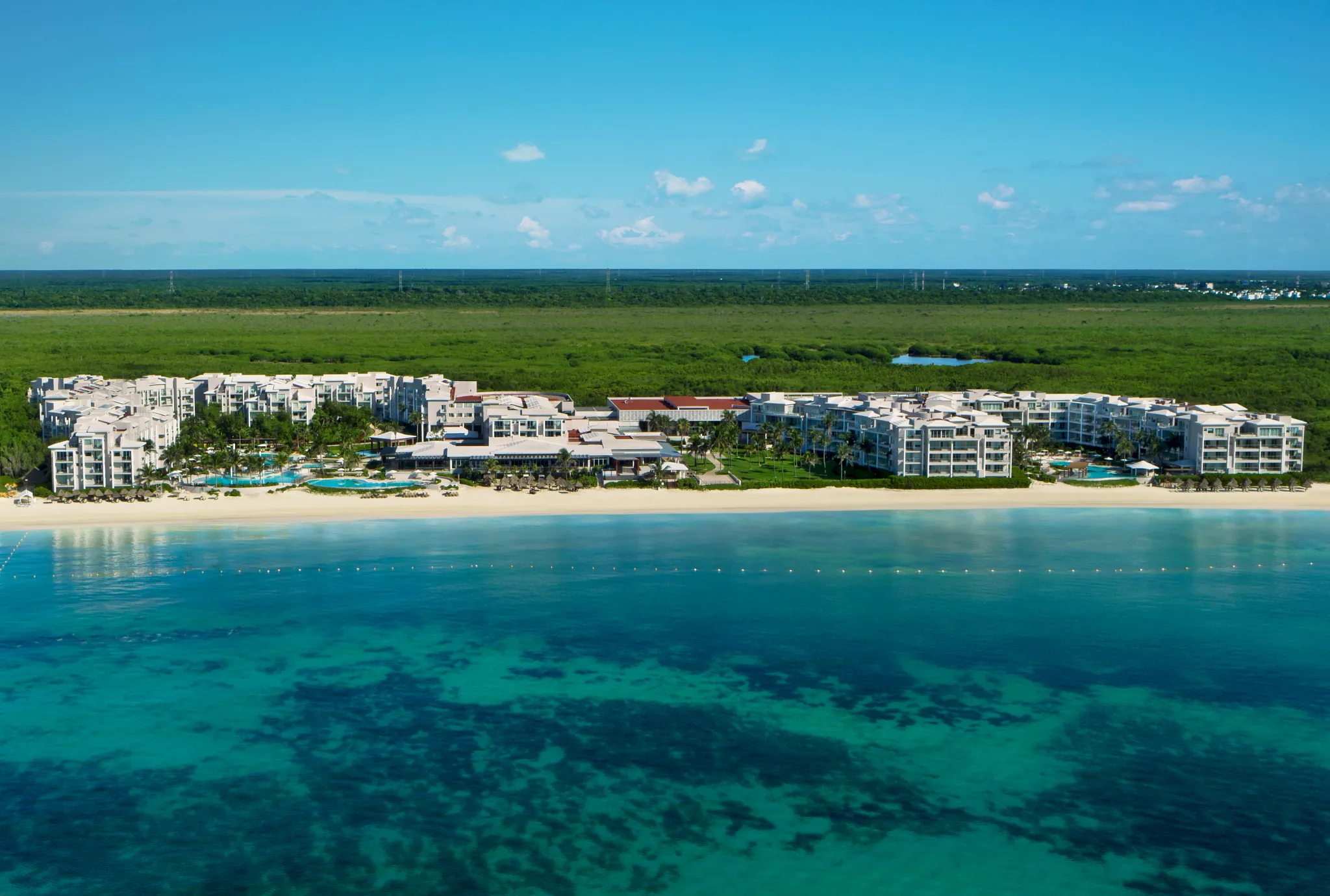 Aerial view of Dreams Jade Resort & Spa Cancun beachfront all-inclusive with pools, palm-lined grounds, and turquoise Caribbean water.