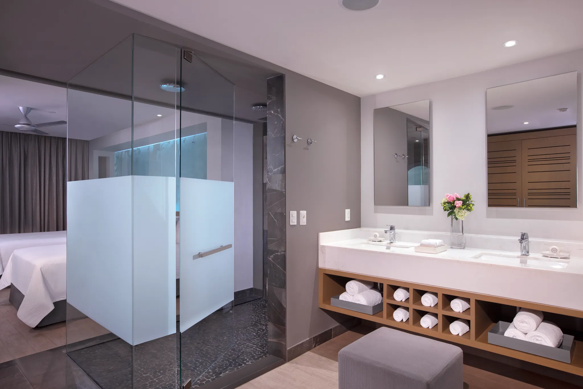 Modern bathroom in the Xcelerate Junior Suite Ocean View at Breathless Riviera Cancun featuring a glass-enclosed rain shower and double vanity.