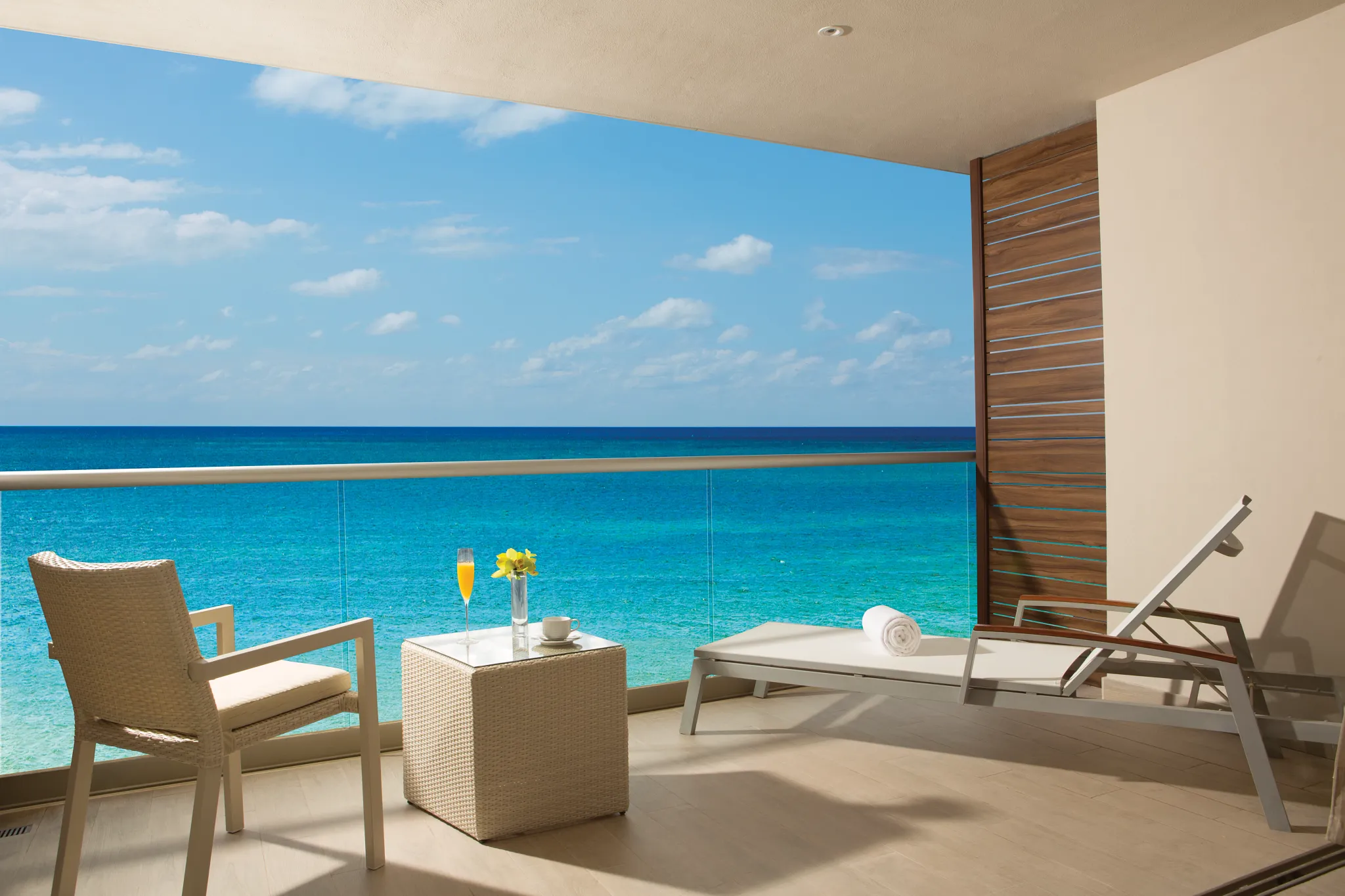 Private oceanfront terrace of the Xhale Club Junior Suite at Breathless Riviera Cancun with lounge seating and panoramic Caribbean Sea views.