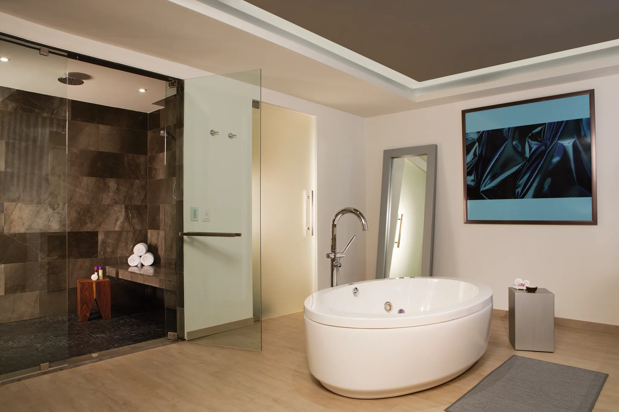 Luxurious bathroom in the Xhale Club Presidential Suite at Breathless Riviera Cancun featuring a freestanding whirlpool tub, glass-enclosed rainfall shower, and modern finishes.
